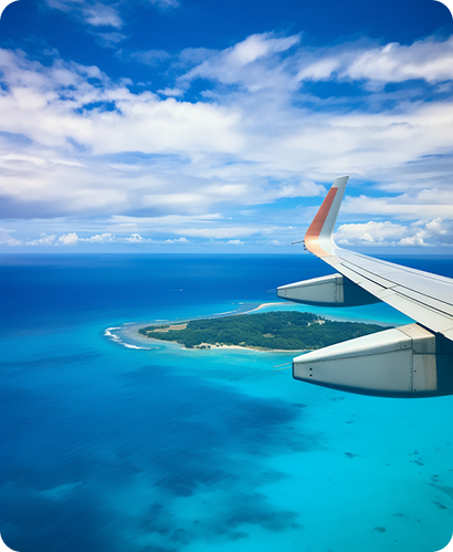 Airplane wing view over tropical turquoise waters and islands with blue sky and clouds